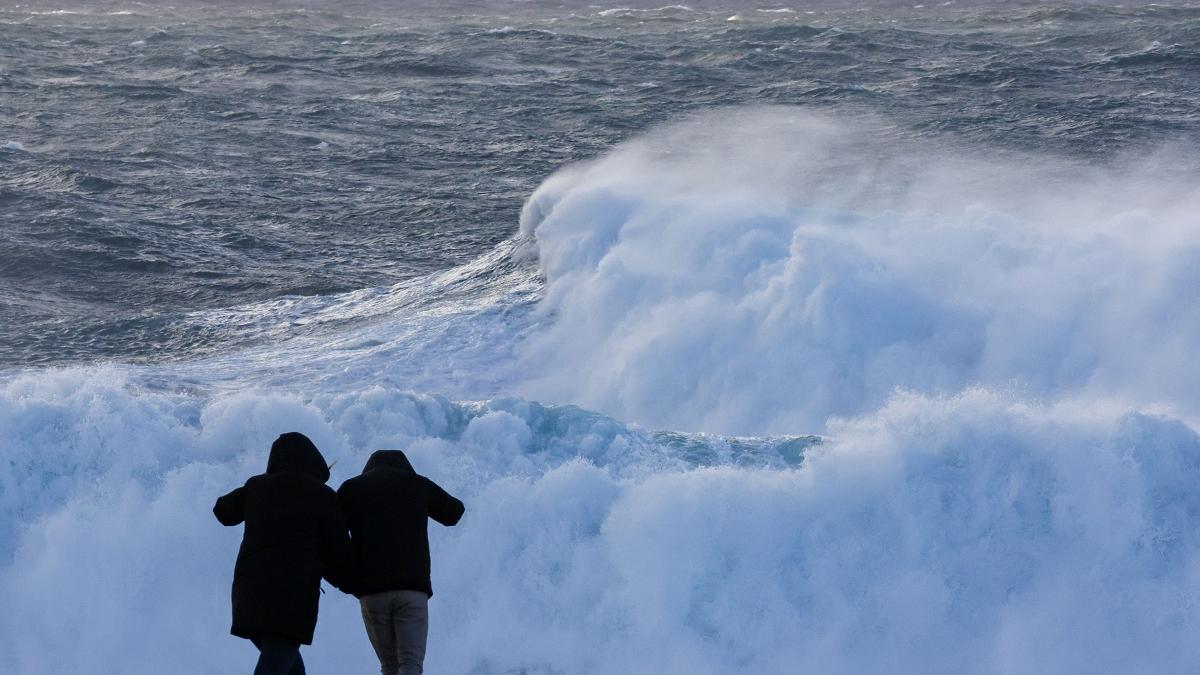 Dos turistas observan el oleaje en Muxía este miércoles