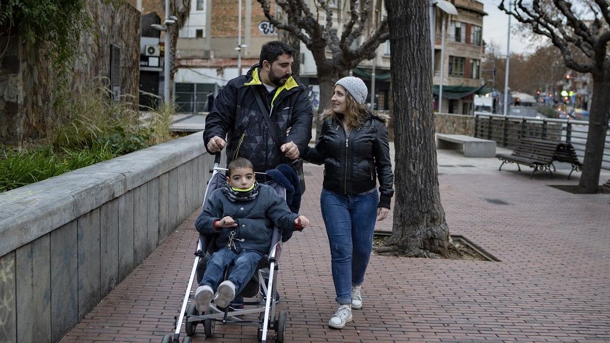 Íker, de 7 años y con el síndrome de KBG, junto a sus padres, Verónica Ramón y Juan Manuel Heredia, en una calle de Santa Coloma de Gramenet.