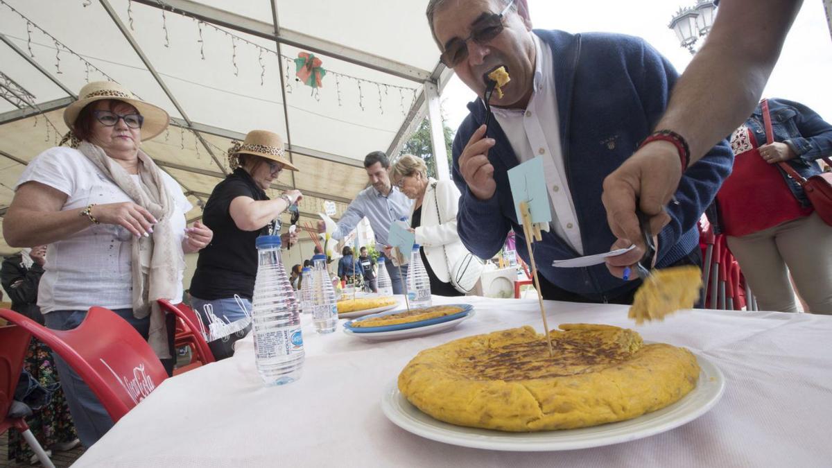 El edil Alfonso Pereira, probando una de las tortillas participantes en la carpa de la plaza del Conceyín. | Miki López