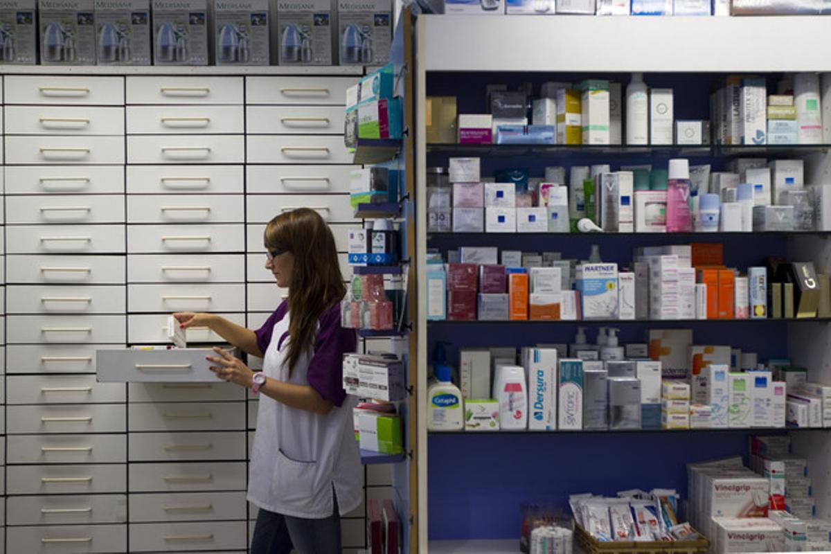Una farmacèutica busca un medicament, en una farmàcia de Barcelona.