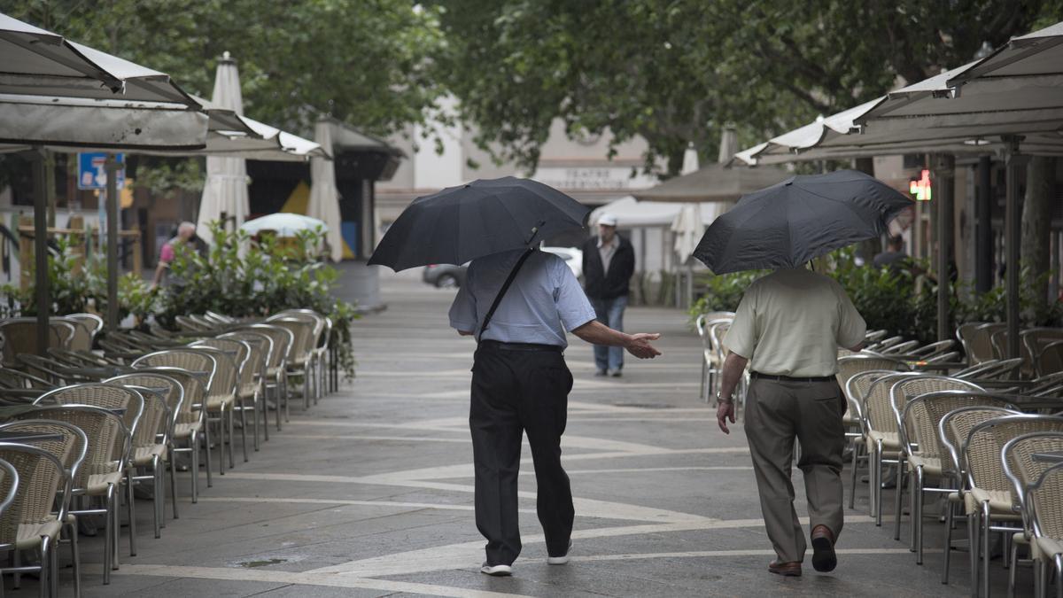 Dos homes al Passeig Pere III de Manresa durant un temporal de pluja