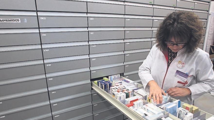 Una farmacéutica busca medicamentos en una botica de Galicia.