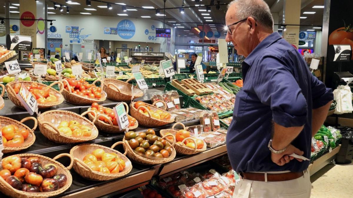 Un home compara els preus de la verdura en un supermercat de Barcelona. | ACN