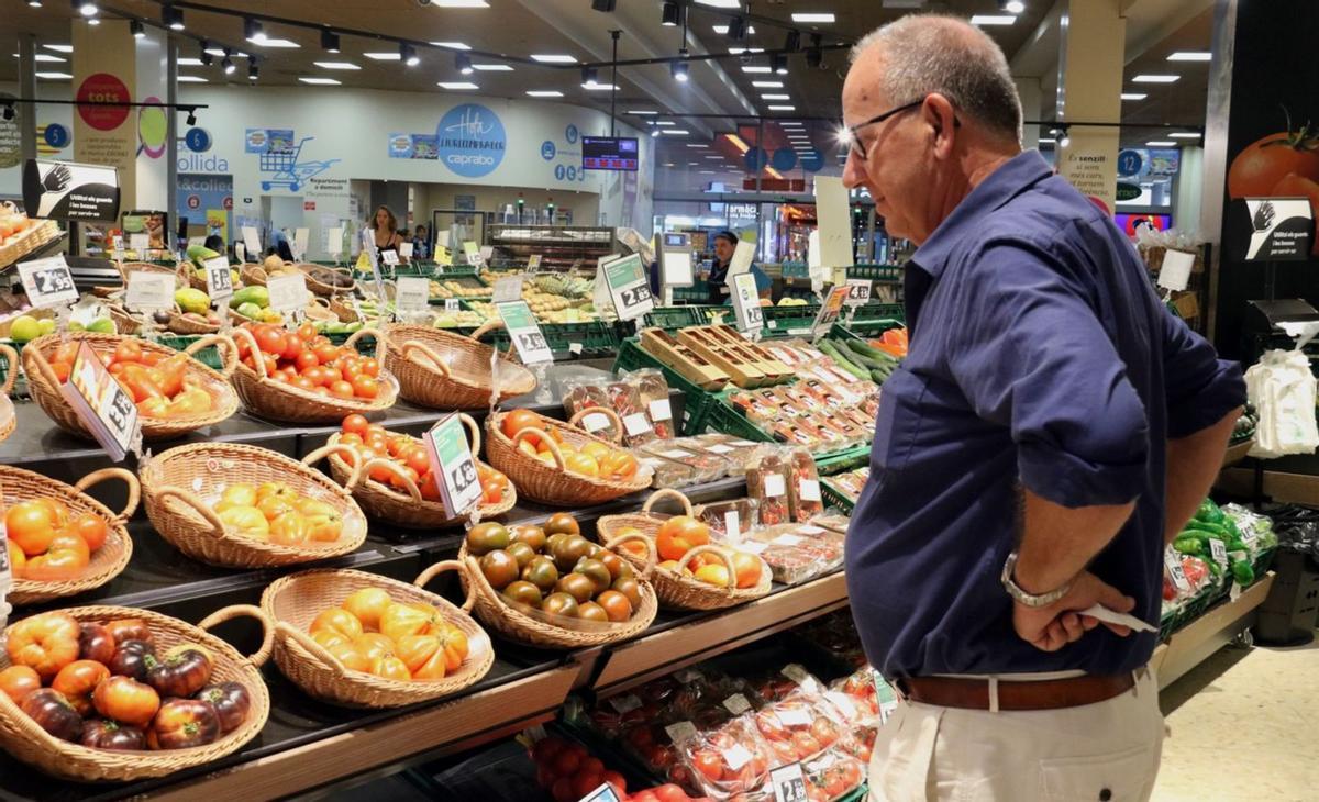 Un home compara els preus de la verdura en un supermercat