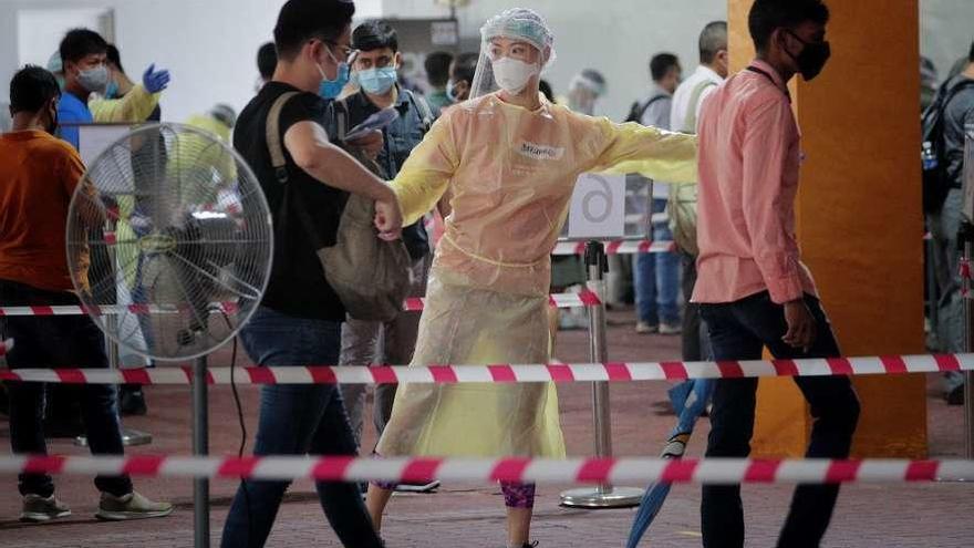 Una enfermera dirige las colas de personas que se someten a test de coronavirus, ayer en Singapur. Epa
