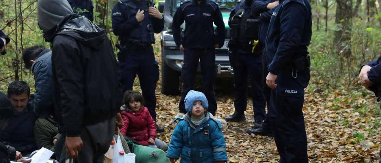 Una familia iraquí rodeada por la policía polaca en la frontera entre Polonia y Bielorrusia.