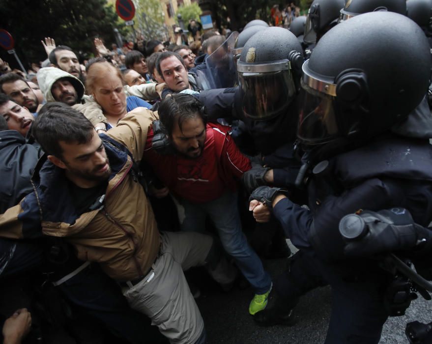 Varias personas intentan abrirse paso entre los agentes policiales.