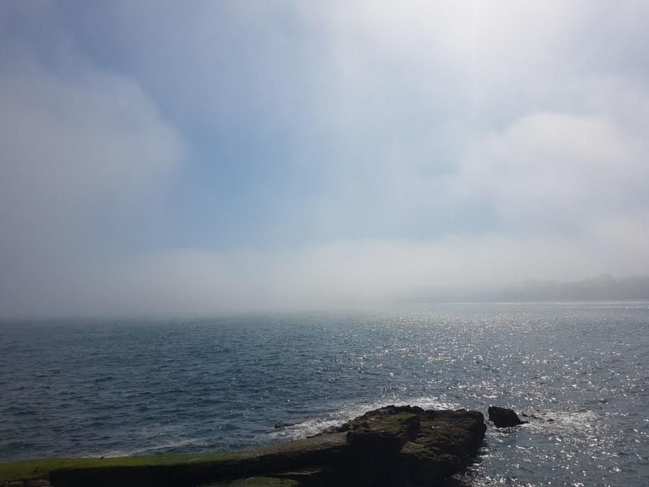 La bruma chafa el día de sol en la costa de Gijón.