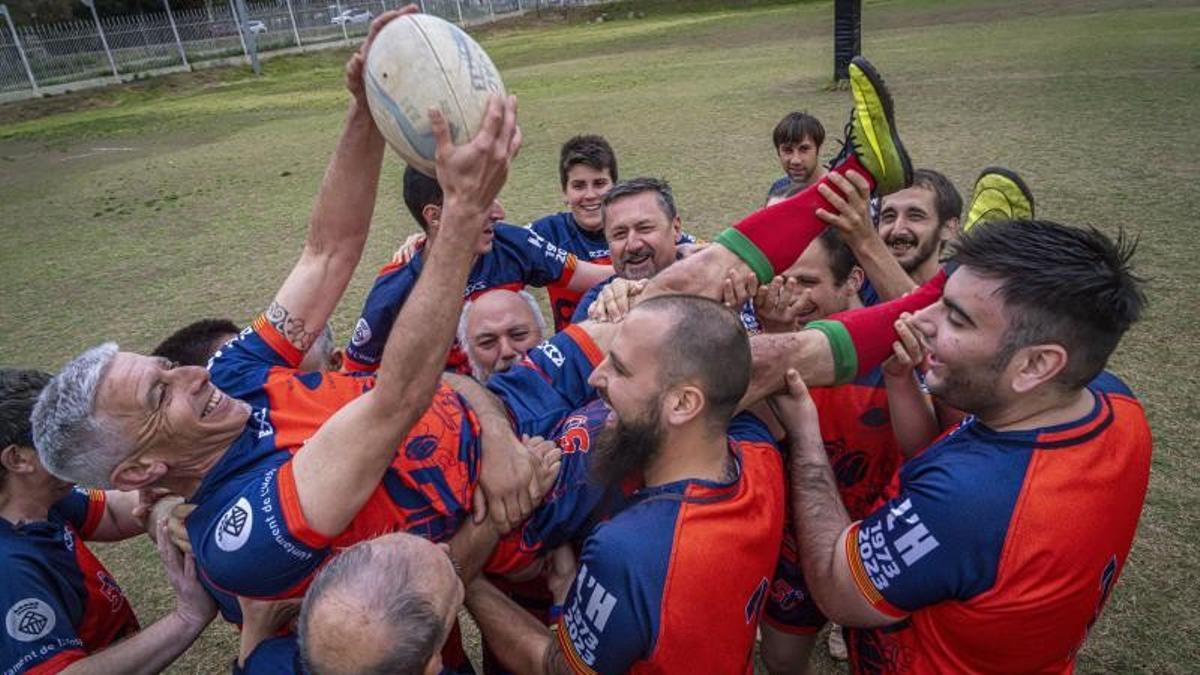 Los jugadores levantan a Peña, entrenador de la sección de rugby inclusivo del club hospitalense.