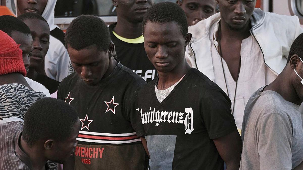 Migrantes subsaharianos llegados ayer a Arguineguín, se reparten mascarillas. | |