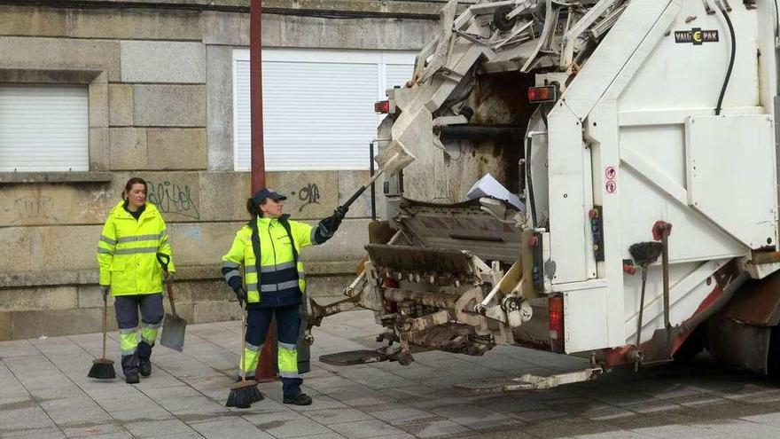 Dos empleadas de la concesionaria Cespa, ayer durante las labores de limpieza en las calles del mercadillo. // Noé Parga