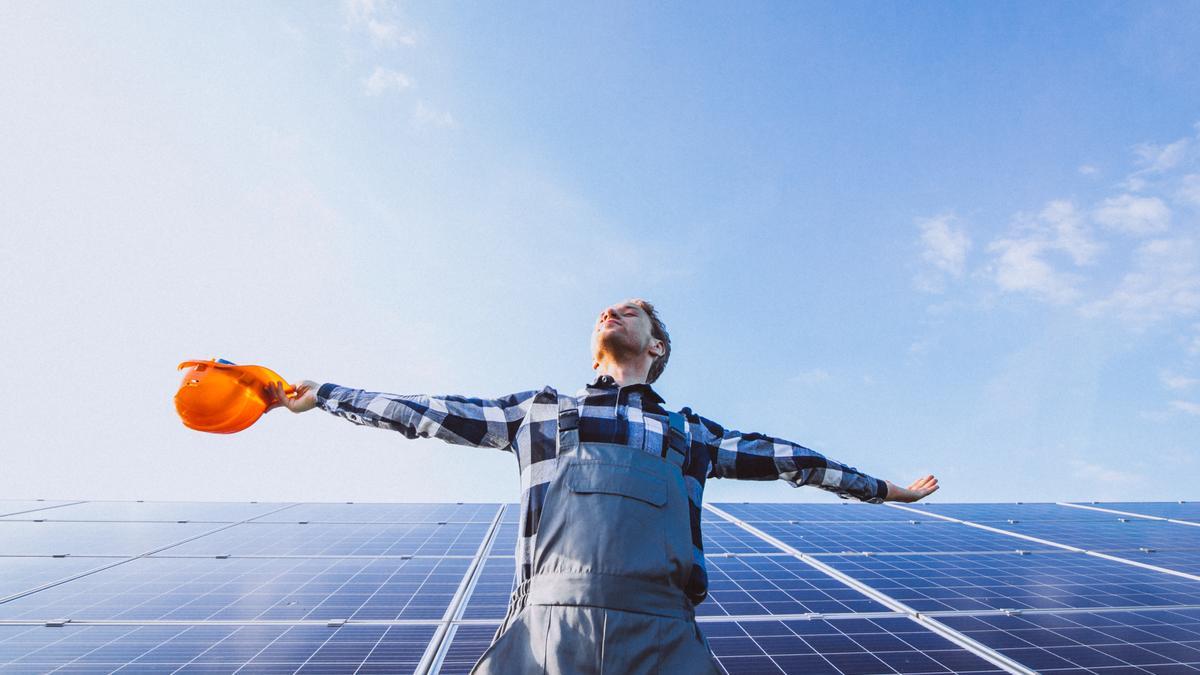 Un trabajador junto a una gran instalación de paneles solares.