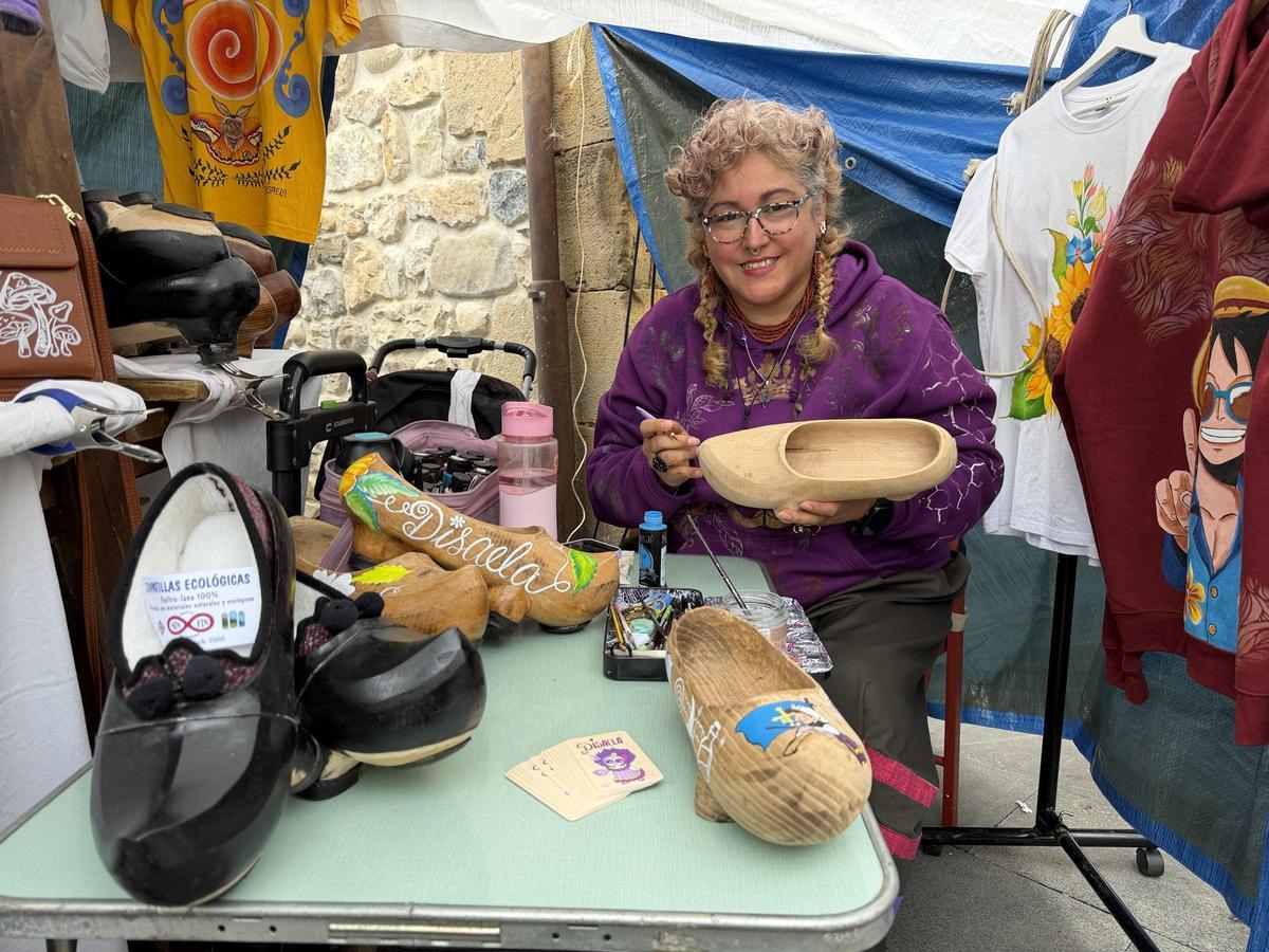 "Disaela" (Diana Bernal) decorando unas madreñas en su puesto del Mercáu d'Artesanos, en Arenas.
