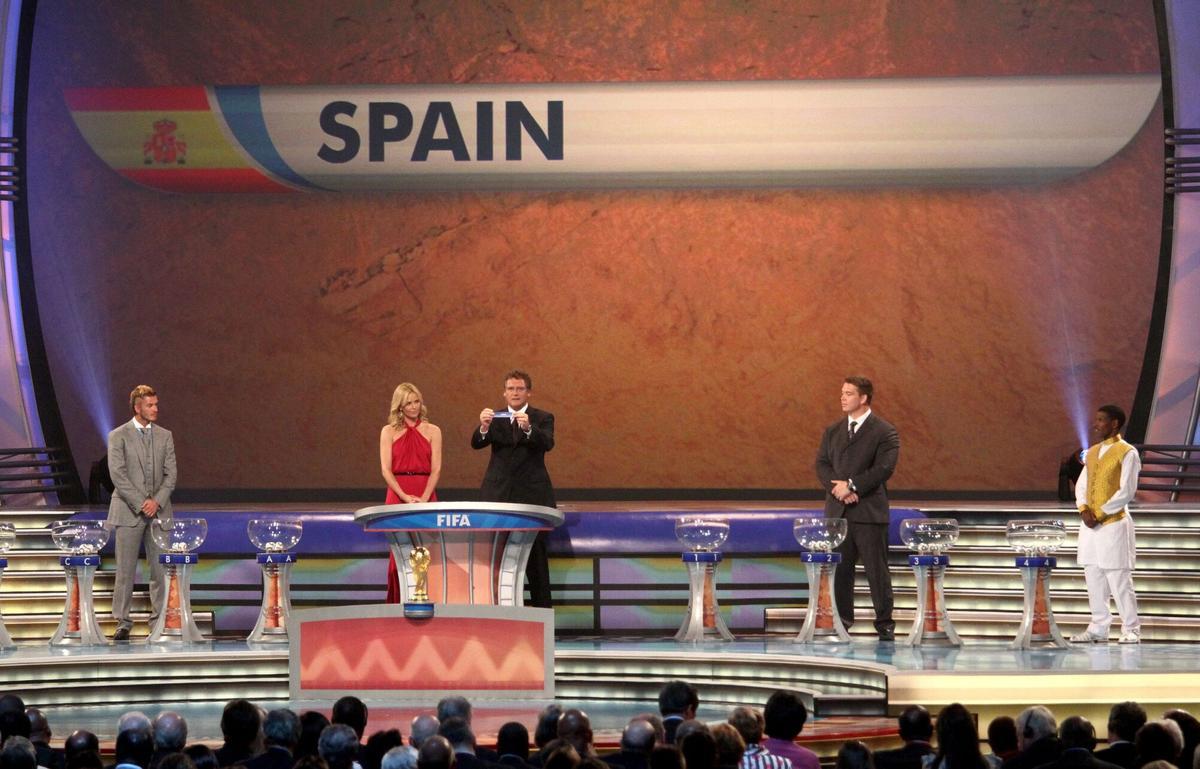 CIUDAD DEL CABO (SUDÁFRICA) 4/12/2009.- El secretario general de la FIFA, Jerome Valcke (3ro d), y la actriz sudafricana Charlize Theron (2da i), sacan el nombre de España de la bola durante la ceremonia del sorteo de grupos de la fase final del Mundial de Fútbol de Sudáfrica 2010 en Ciudad del Cabo, Sudáfrica, hoy, viernes 4 de diciembre de 2009. En la fotografía, la estrella del fútbol inglés David Beckham (i), el capitán sudafricano de rugby Jon Smit (2do d) y el legendario fondista etíope Haile Gebrselassie (d). España ha quedado en el Grupo H junto a Suiza, Honduras y Chile. EFE/Kim Ludbrook SUDÁFRICA-MUNDIAL 2010-SORTEO. DEPORTES. FUTBOL. SELECCIONES NACIONALES. SELECCION ESPAÑOLA .MUNDIAL DE SURAFRICA 2010. SORTEO DE GRUPOS.