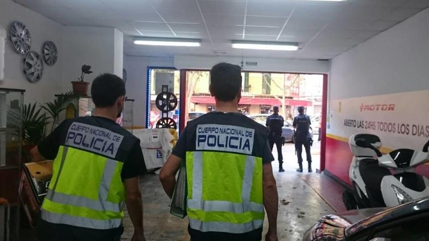 Dos policías, durante el registro en el taller que regentaba el sospechoso.