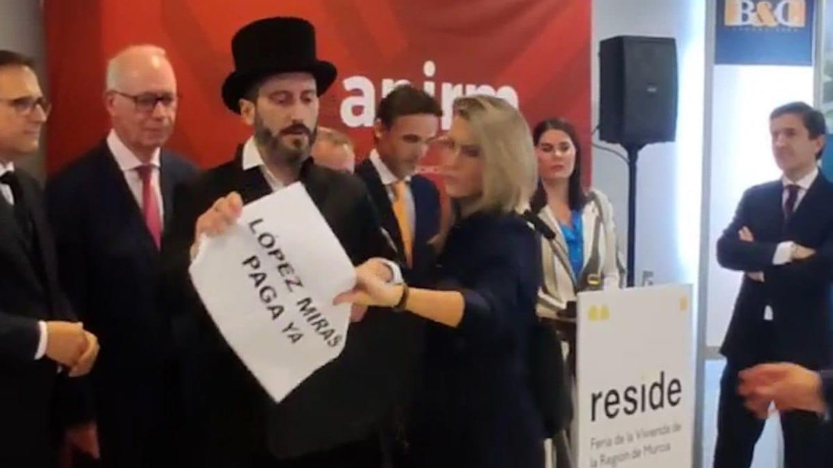 Egío vestido como cobrador del frac y con una pancarta, en la feria de vivienda