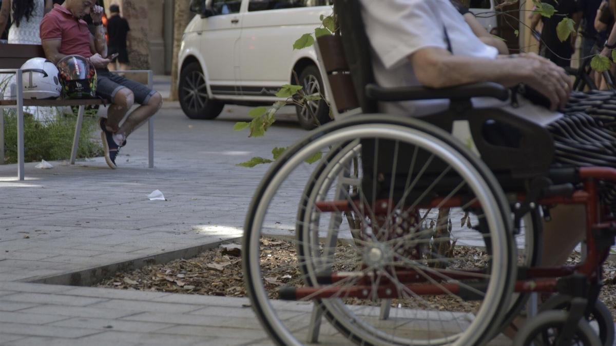 Fotografía de archivo de una persona mayor en silla de ruedas en la calle.