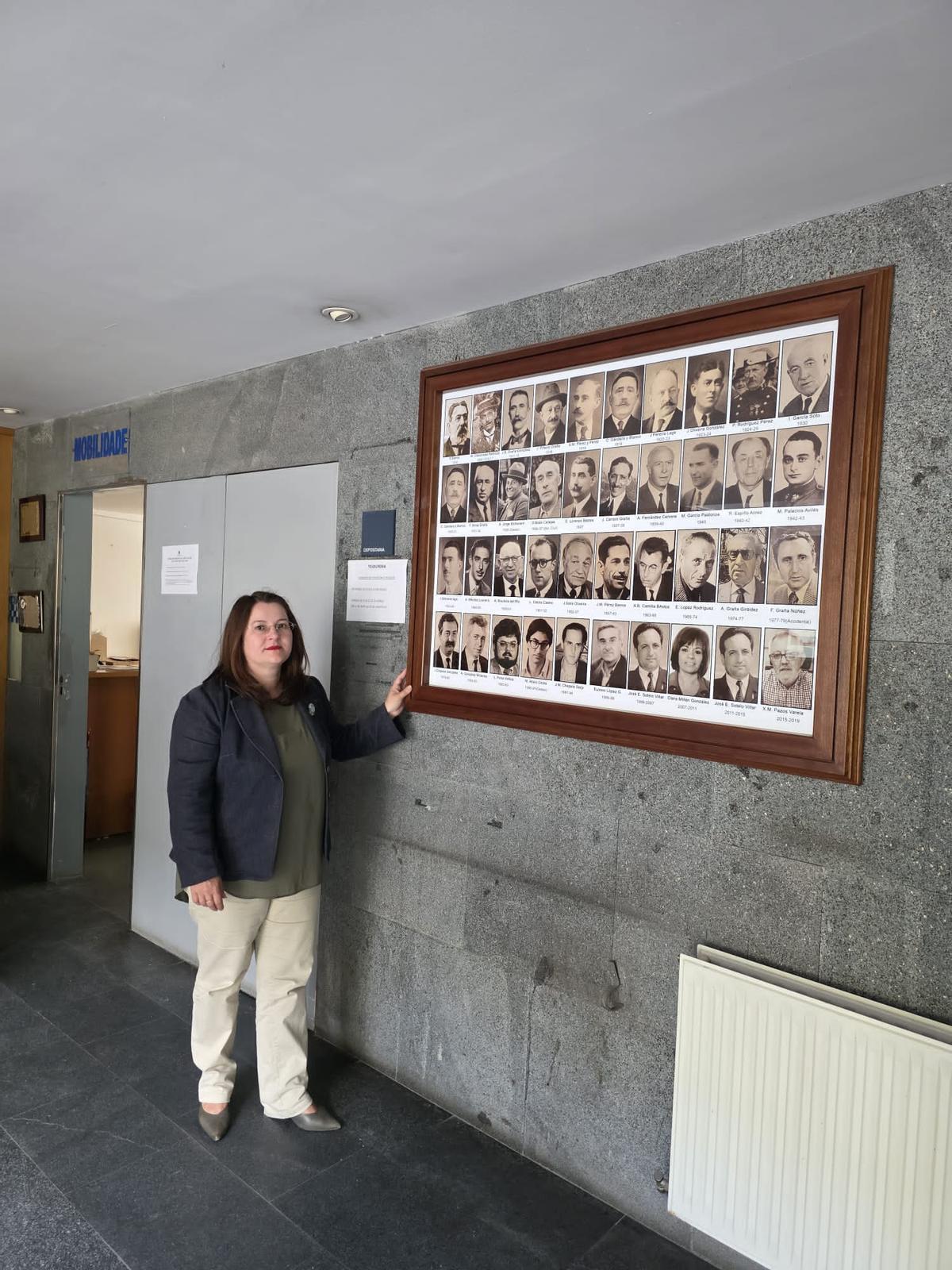 La regidora de Cangas, Araceli Gestido, junto al cuadro de alcaldes y alcaldesas en la entrada del Concello en donde aparece Óscar Boán (segunda fila arriba, cuarto por la izquierda)