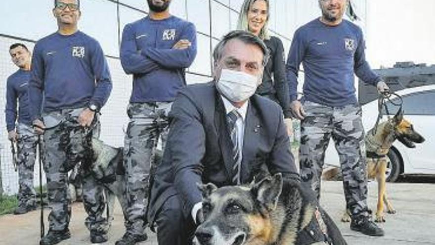 Bolsonaro posa con mascarilla junto a un perro y varios policías sin protección, antes de un acto en Brasilia.