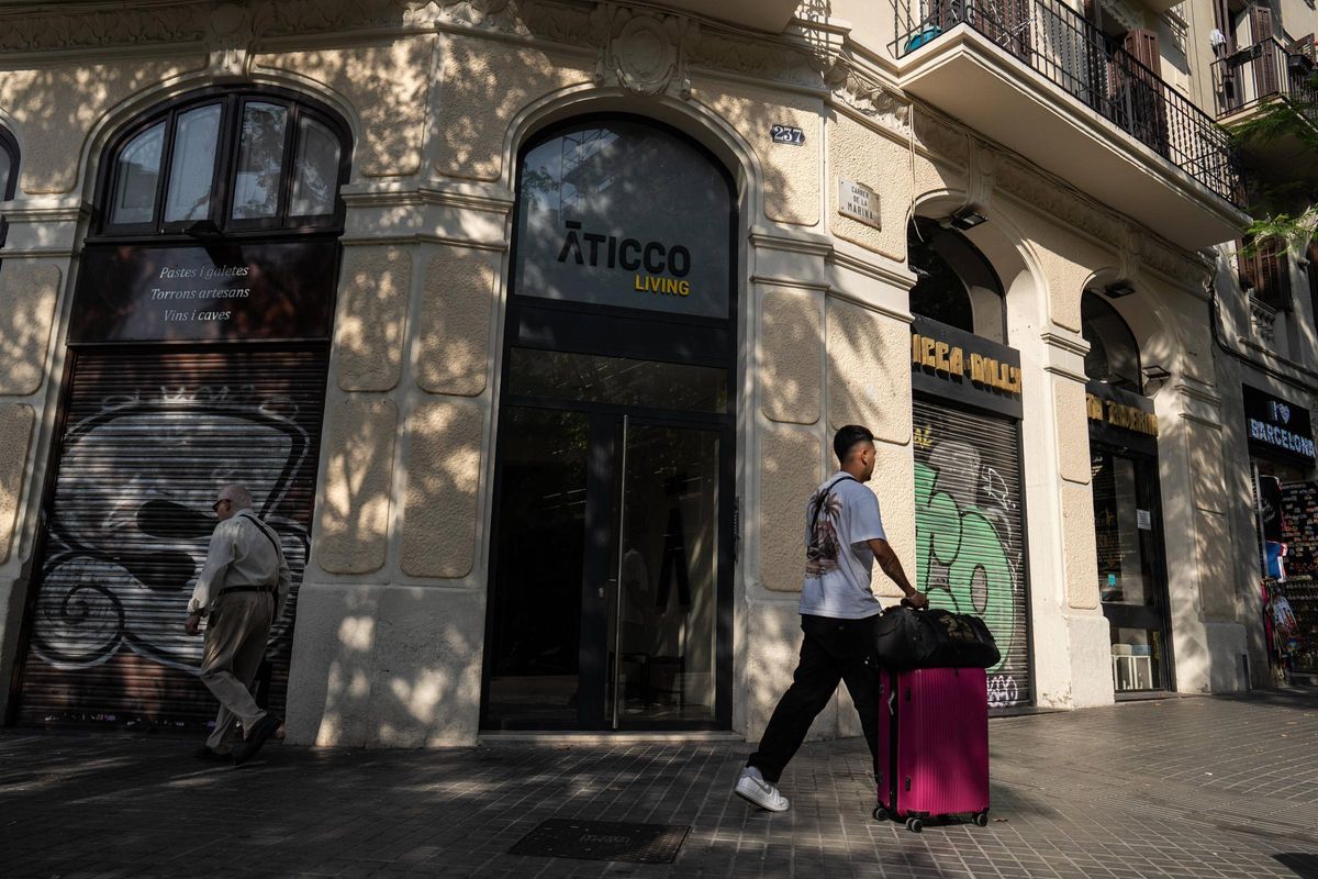 Vista de la entrada de Aticco Living en el Carrer Marina con un turista de paso.