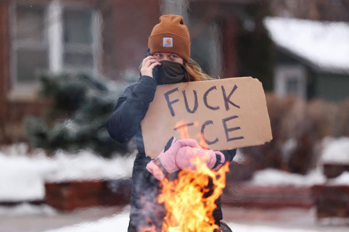 EDITORS NOTE: Graphic content / A woman talks on the phone as she holds a sign while standing along the street where 37-year-old Renee Nicole Good was shot and killed at point blank range on January 7 by a US Immigration and Customs Enforcement (ICE) agent as she apparently tried to drive away from agents who were crowding around her car, in Minneapolis, Minnesota, on January 8, 2026. A US Immigration and Customs Enforcement (ICE) agent shot and killed an American woman on the streets of Minneapolis January 7, leading to huge protests and outrage from local leaders who rejected White House claims she was a domestic terrorist. (Photo by CHARLY TRIBALLEAU / AFP). Graphic content