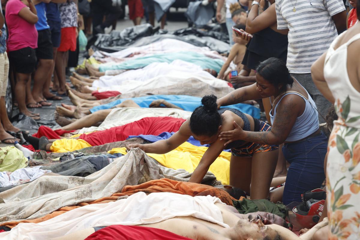 Una mujer observa un cuerpo sin vida en una calle este miércoles, en Río de Janeiro (Brasil). EFE/ Antonio Lacerda. ATENCIÓN EDITORES: CONTENIDO GRÁFICO EXPLICITO