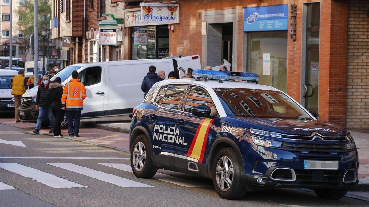 Un vehículo policial y una furgoneta de una funeraria, junto al portal del inmueble en el que fue hallada la víctima.