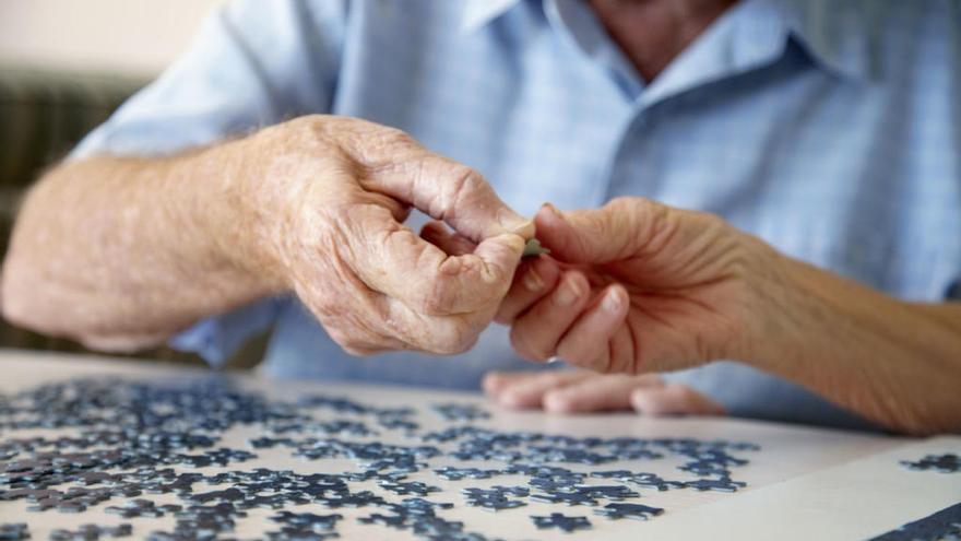 Una persona anciana hace un puzle, una actividad recomendada para el envejecimiento activo.