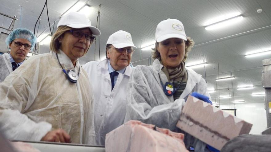 La ministra (dcha) con un trozo de pescado, en la visita a la planta Fandicosta, con la conselleira de mar y el presidente de la empresa. Gonzalo Núñez