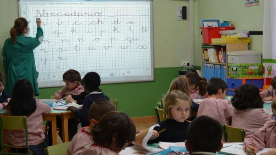 Una maestra enseña caligrafía a los niños más pequeños con una pizarra digital.