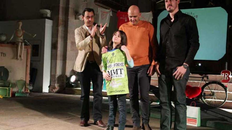 Una niña recibe una camiseta firmada por los jugadores del equipo de balonmano ante Maíllo.