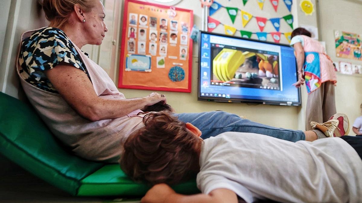 Un pequeño alumno de infantil observa a una de sus maestras.