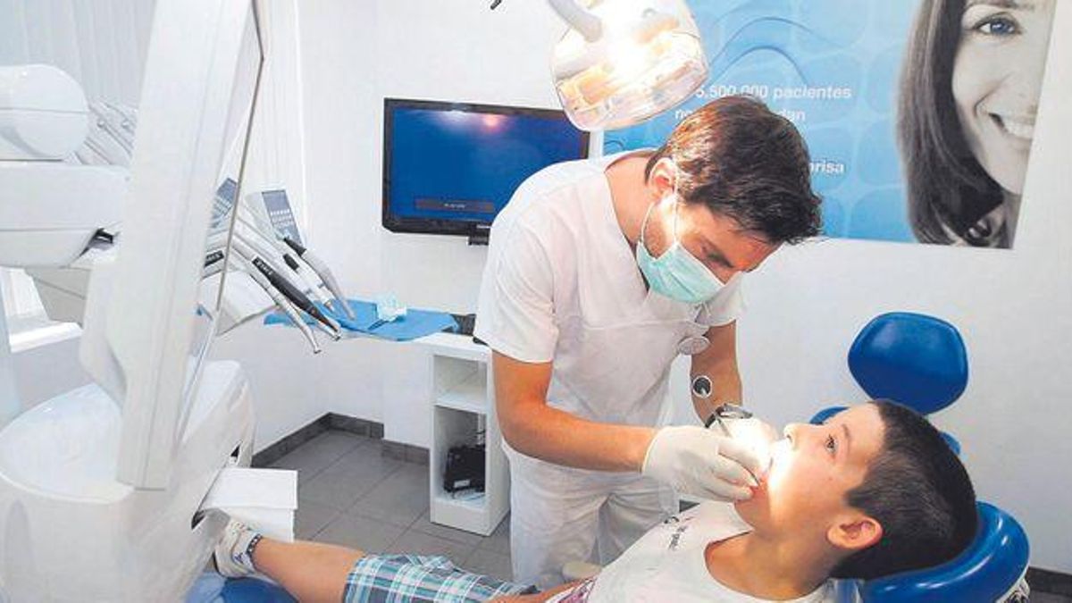 Un dentista atiende a un niño en consulta.
