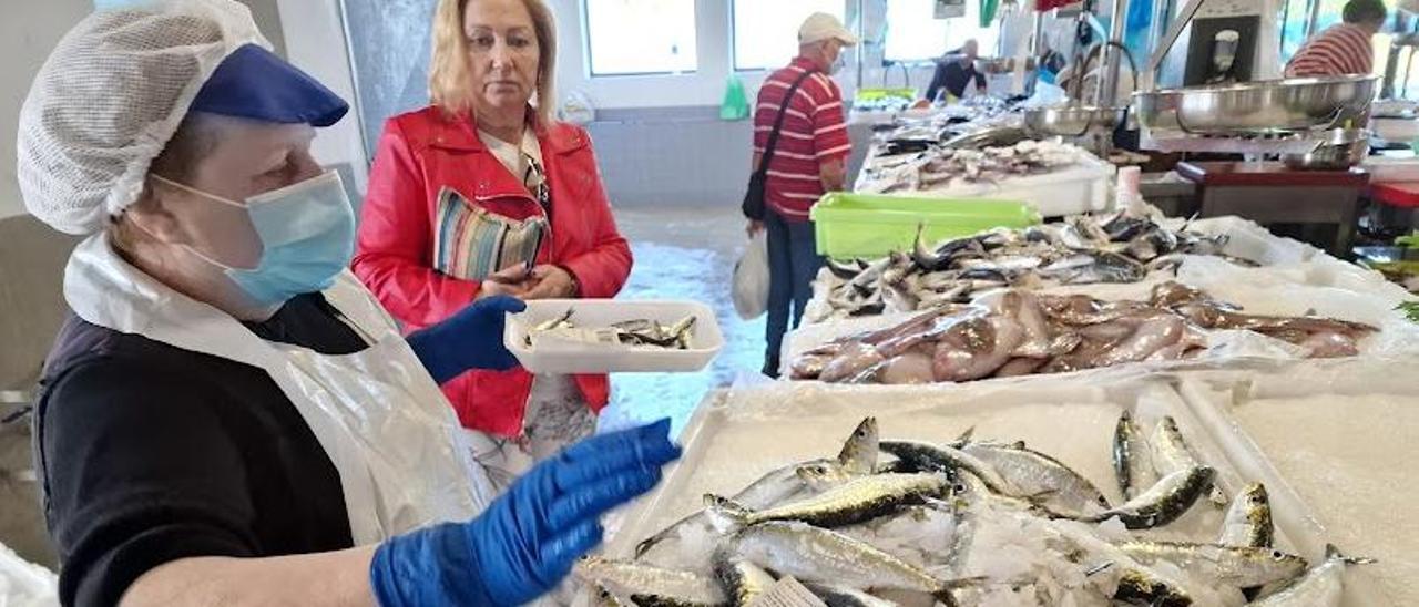 María del Carmen Soto, vendedora de la plaza de abastos de Vilagarcía, con una bandeja de “xoubiñas” en la mano, vendidas a 18 euros el kilo, ante una caja de sardinas, que despachó a 8 euros, ayer.