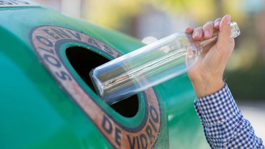 Un ciudadano recicla una botella de cristal.