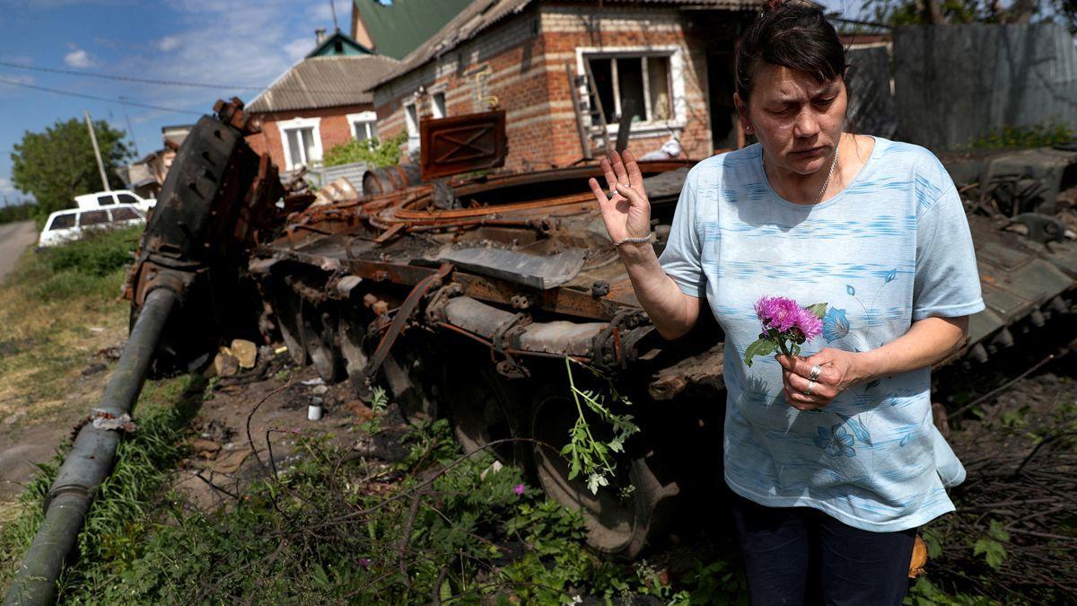 Una mujer recoge flores cerca de un tanque ruso destruido, en la localidad ucraniana de Mala Rohan