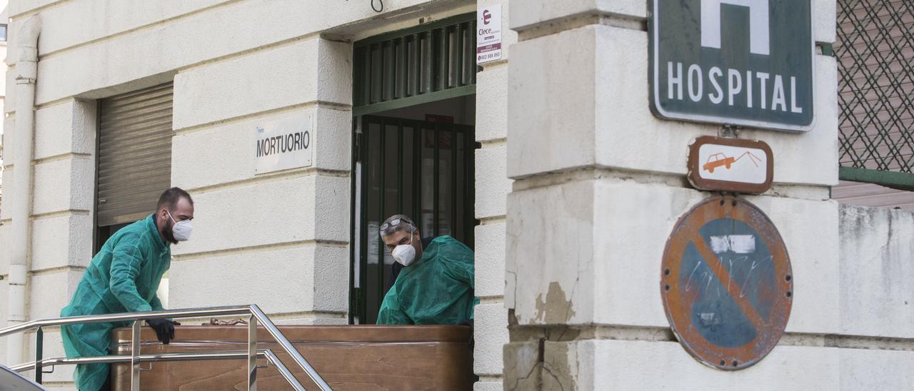 Dos enfermeros sacan un féretro de un hospital valenciano en febrero pasado.