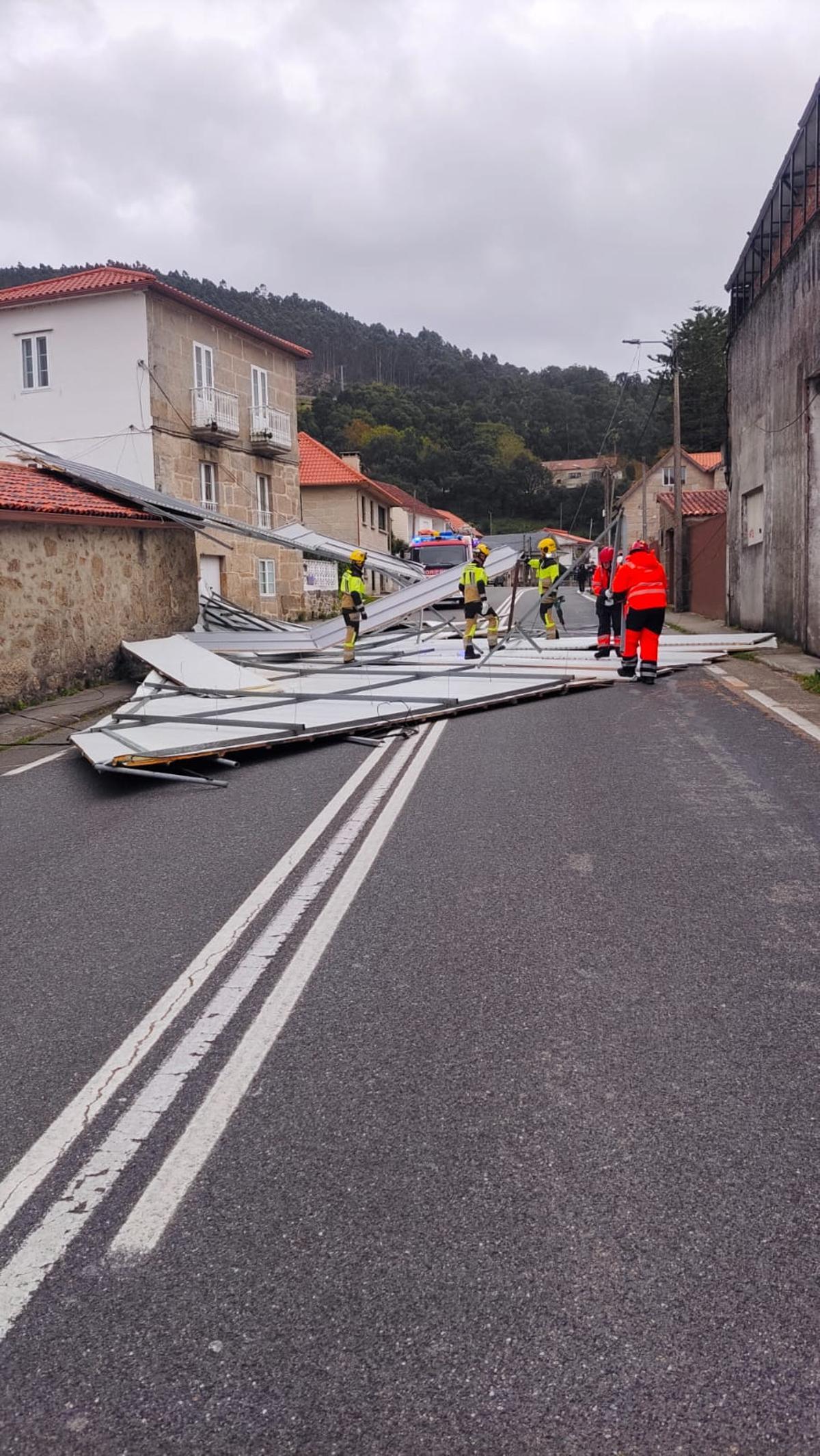 Los equipos de emergencias, ante el tejado desprendido sobre la PO-551 en Domaio