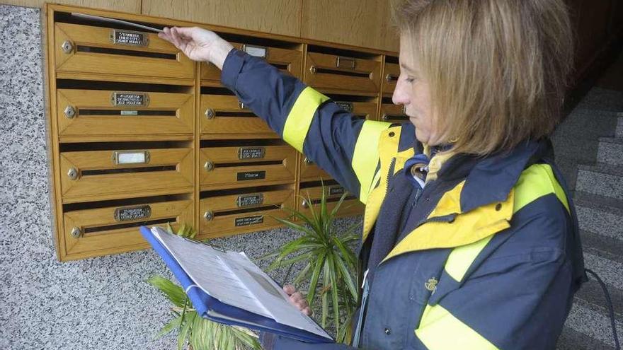 Una cartera reparte los envíos postales en un edificio de A Coruña.