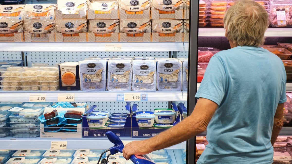 Un hombre mira los productos y los precios de uno de los lineales de un supermercado de las Islas.