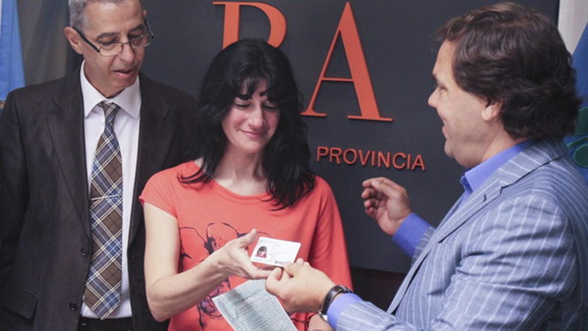La madre de Luana, Gabriela, recibe el documento de identidad de su hija de manos del jefe de Gabinete del Gobierno provincial de Buenos Aires, Alberto Pérez (derecha), ante el presidente de la comunidad homosexual de Argentina, César Cigliutti.