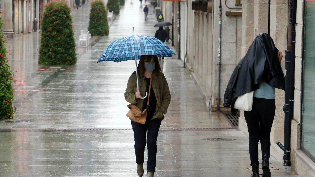 Una mujer pasea por Vigo con paraguas y mascarilla. // Marta G. Brea