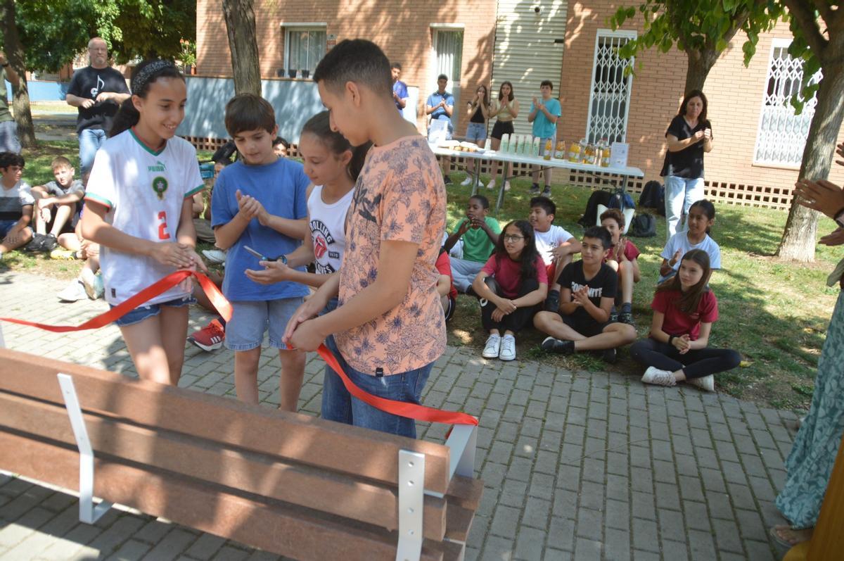 Alumnes representants de cada centre educatiu tallant la cinta per inaugurar el banc.