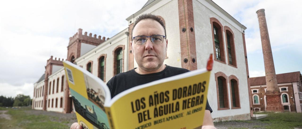 Francisco Bustamante, con su libro y ante la fábrica del Águila Negra de Colloto, hoy convertida en Bien de Interés Cultural. | I. Collín
