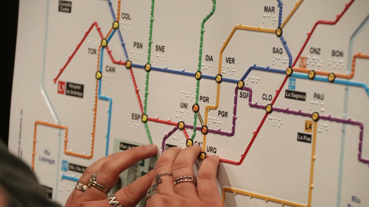 Una persona ciega interpreta uno de los nuevos mapas táctiles del metro de Barcelona