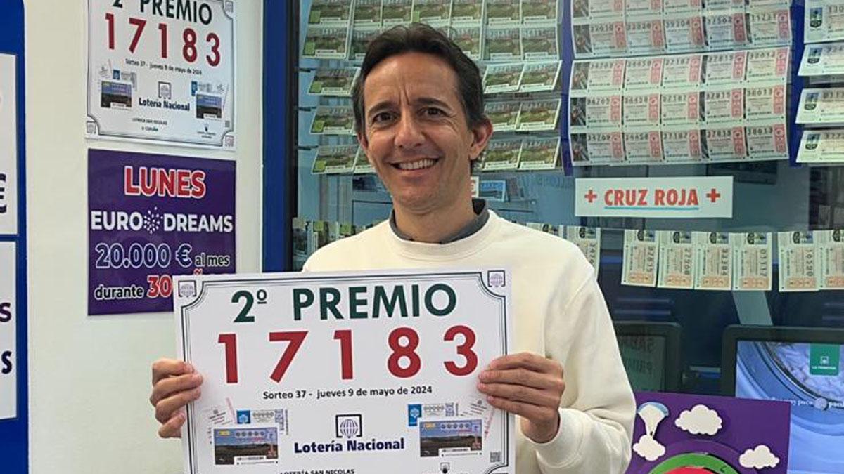 Iván González muestra el cartel del premio repartido por la administración de Loterías San Nicolás.
