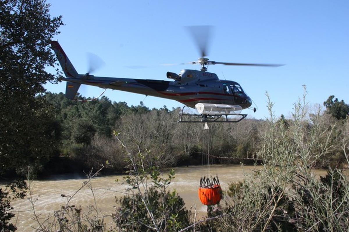 Un dels helicòpters recull aigua durant les tasques d’extinció.