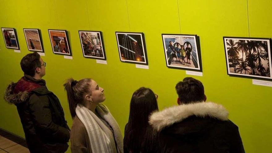 Varias personas observan la exposición de fotografías en el CIDAN.