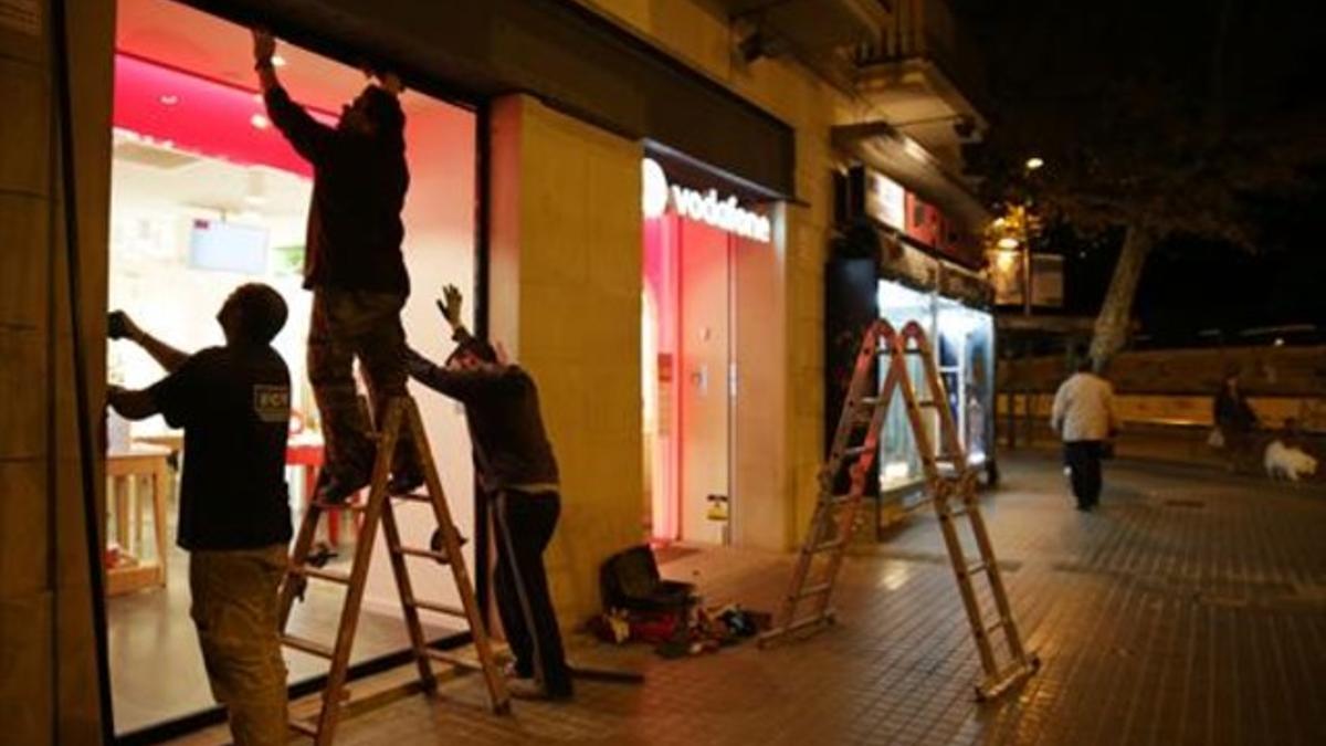 Reparación del escaparate de la tienda de teléfonos de la calle de Manso, ayer por la tarde.