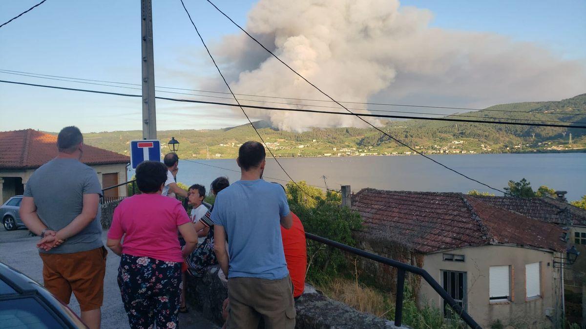 Vecinos de la zona observan la evolución de las llamas al otro lado del embalse.